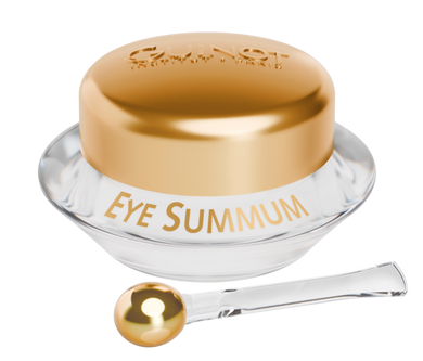 A jar of Guinot EYE SUMMUM Balm with a golden lid, alongside an application brush with a gold-colored handle and a golden tip.